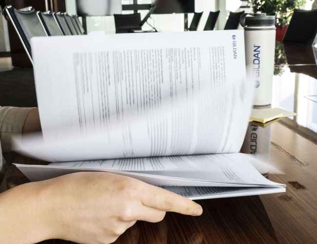 An employee is flipping through a Gildan report in an office.