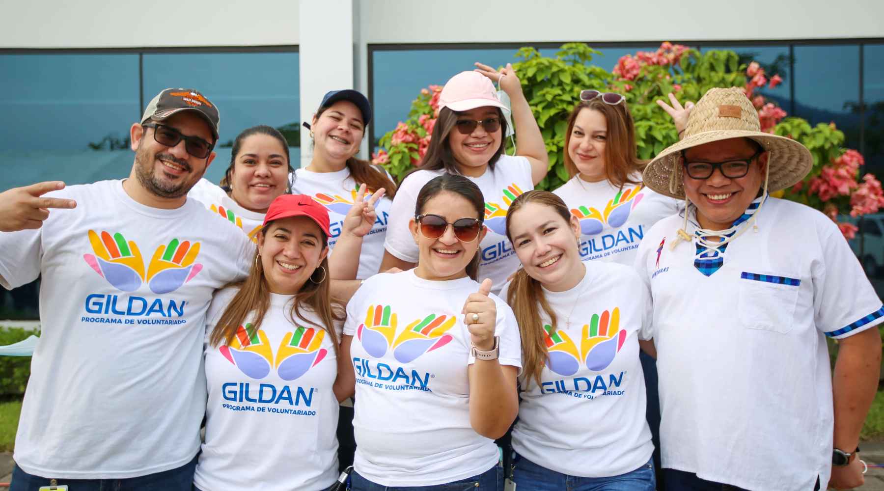 Employees in Honduras are wearing Gildan volunteering shirts and smiling.