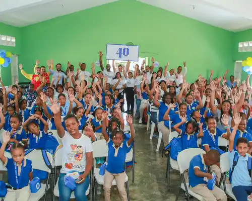 A woman is speaking into a microphone in front of a group of Gildan employees.