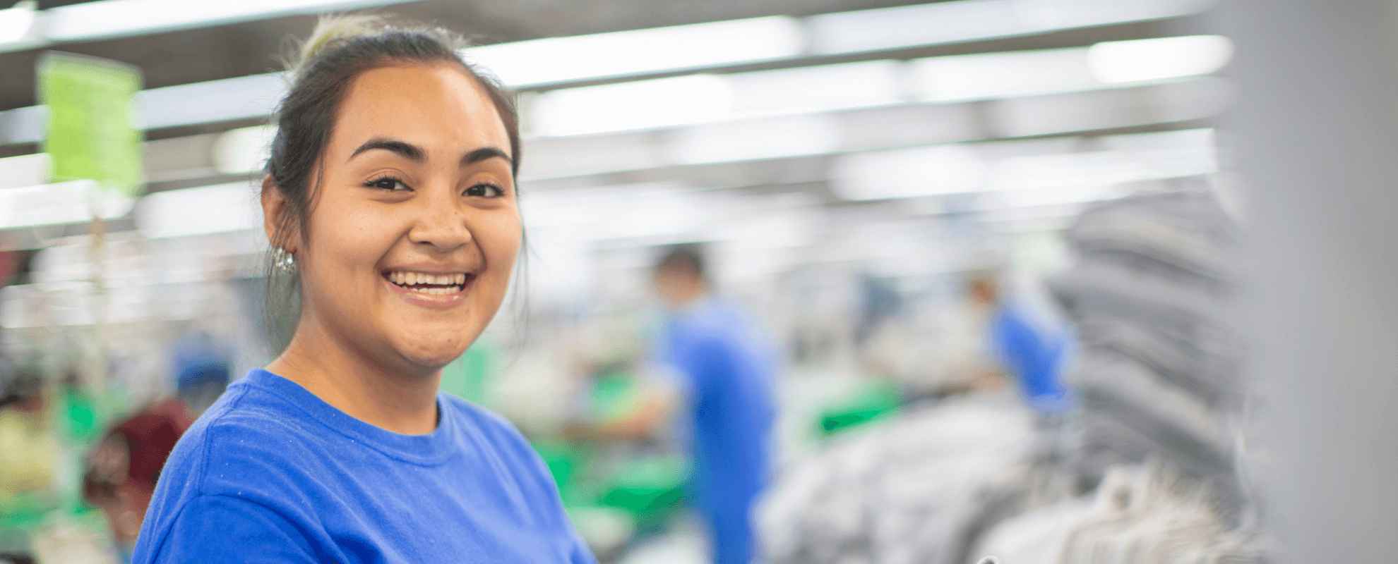 A woman holding a pile of grey folded Gildan shirts.