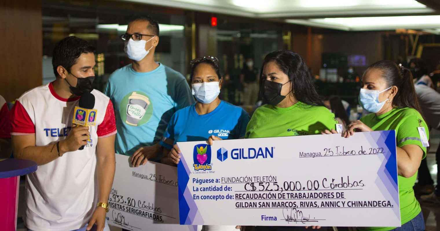A man from Teleton Fundacion is speaking to 3 Gildan employees who are holding up a large cheque.