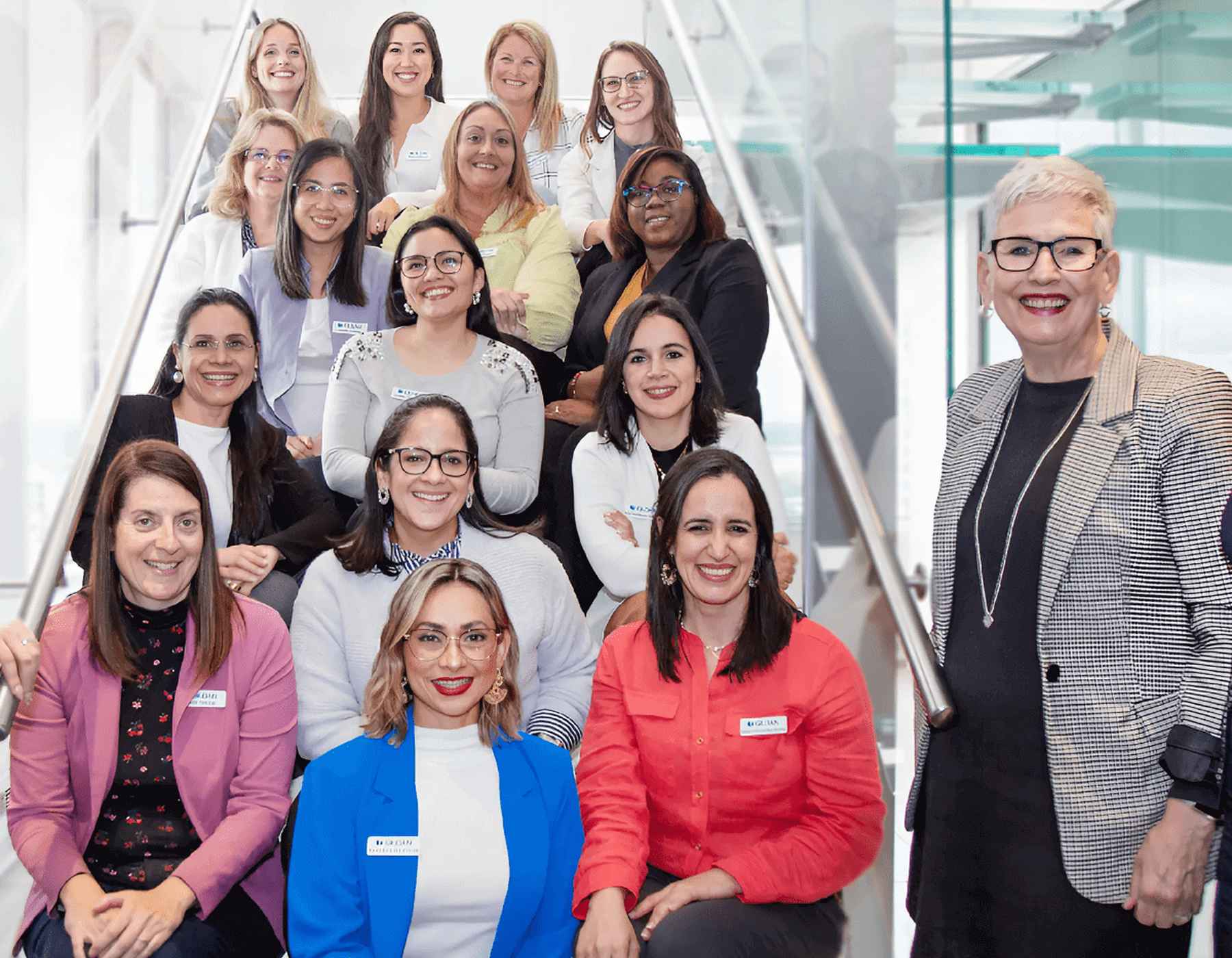 A group of female employees sitting on the staircase at corporate head office in Montreal smiling.