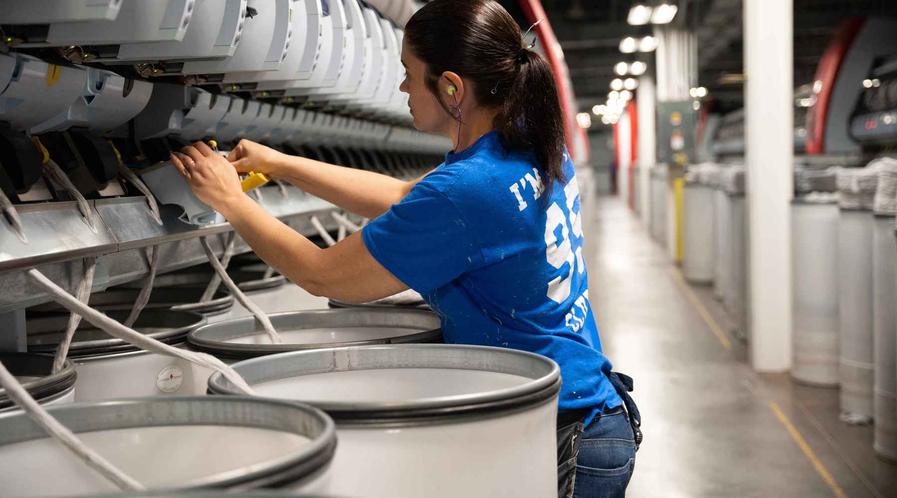 A yarn-spinning employee in the U.S. is operating a machine.