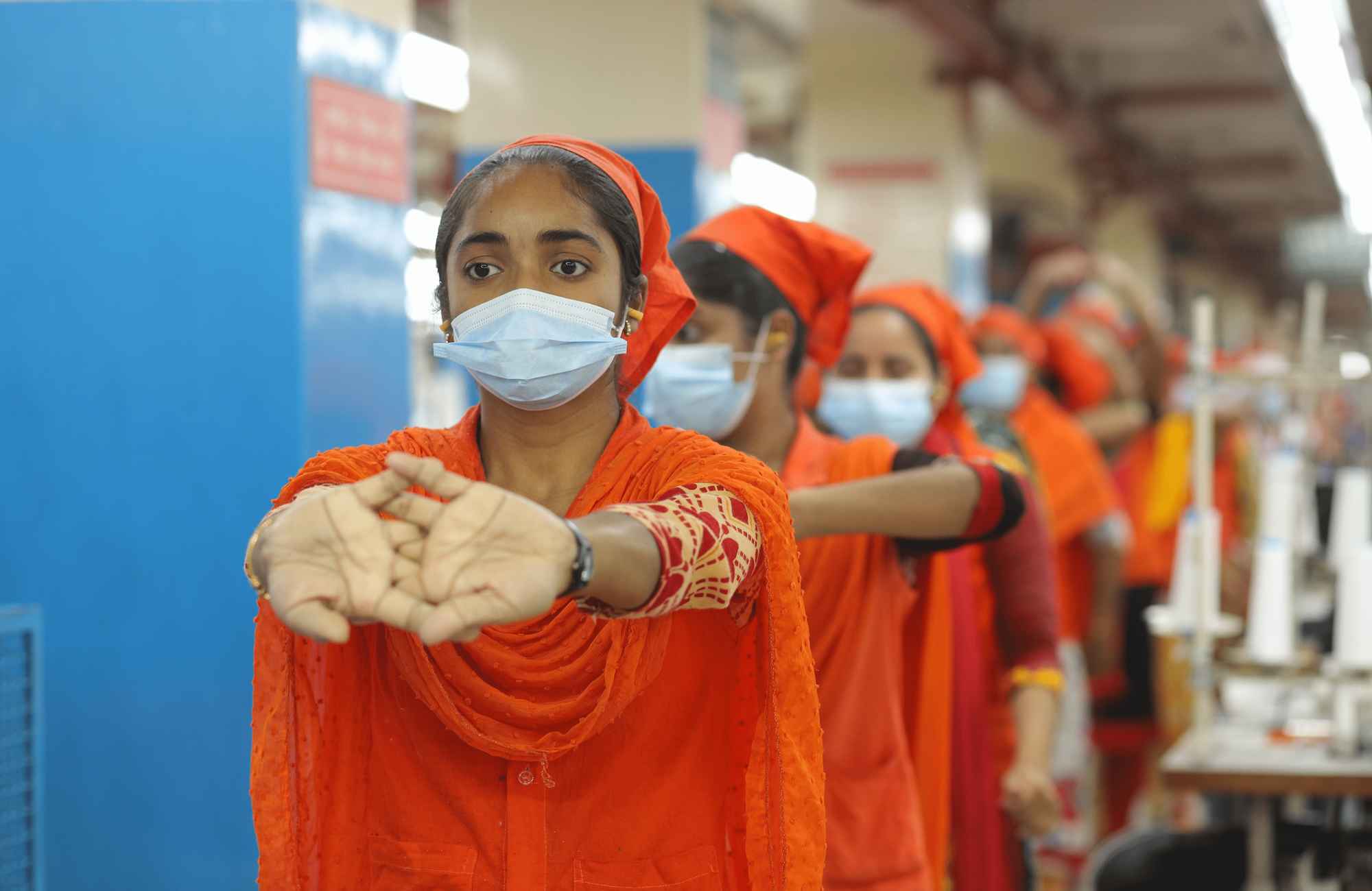 Sewing operators stretching during an ergonomic pause in Gildan's facility