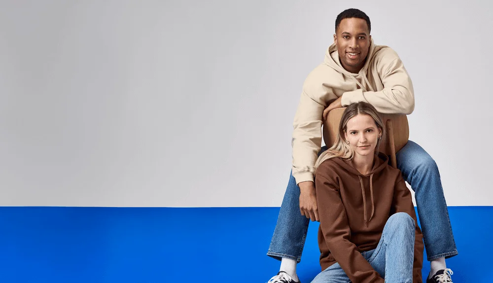 Two models against a white and blue backdrop wearing Gildan clothes